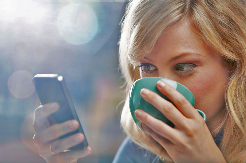 blond woman drinking coffee with smartphone