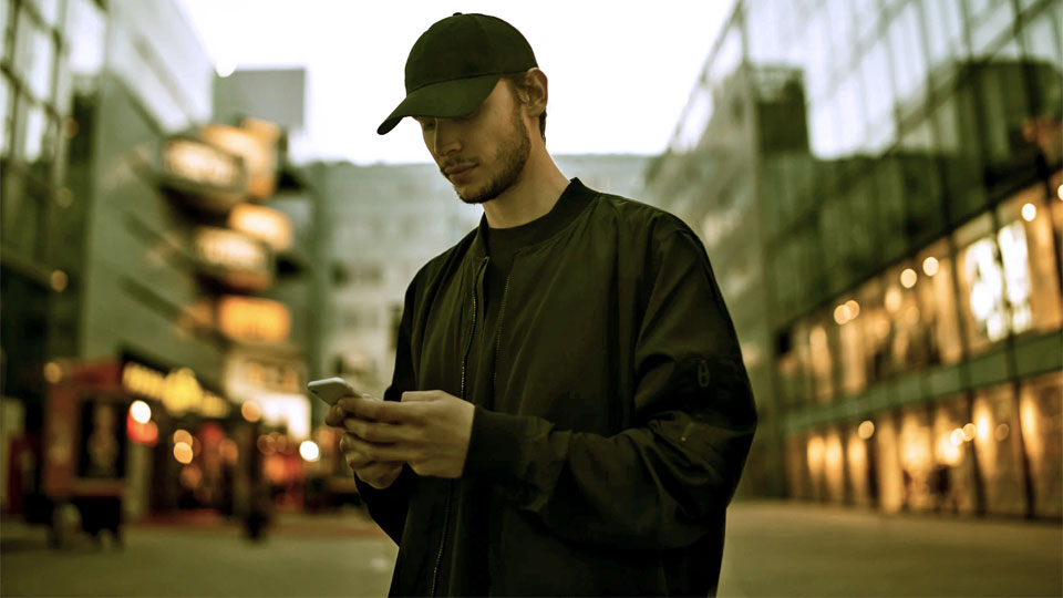 man with clothes and black cap and smartphone in hand