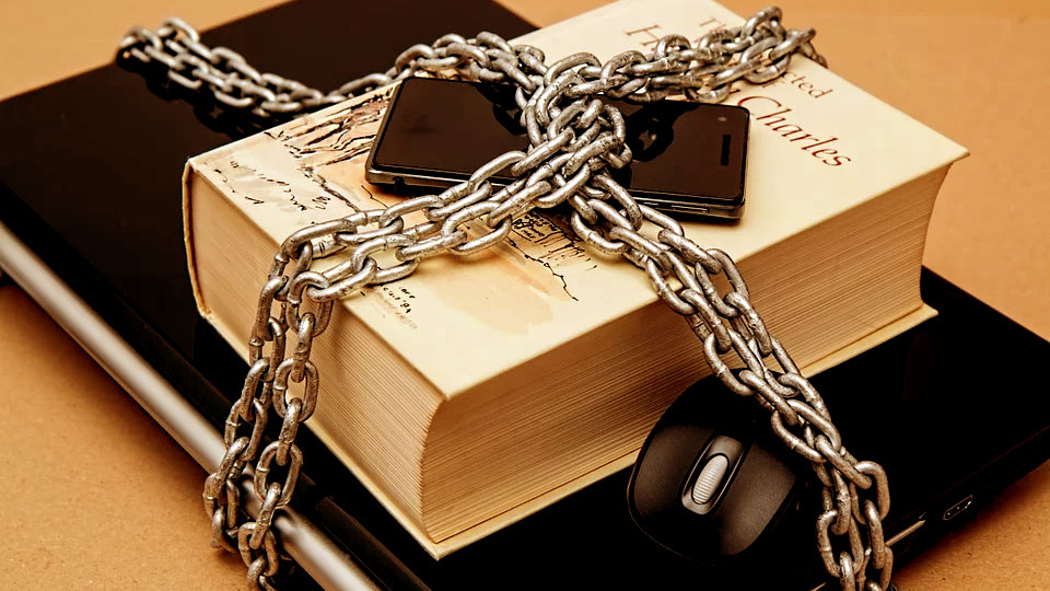 a book, a notebook and a smartphone in chains