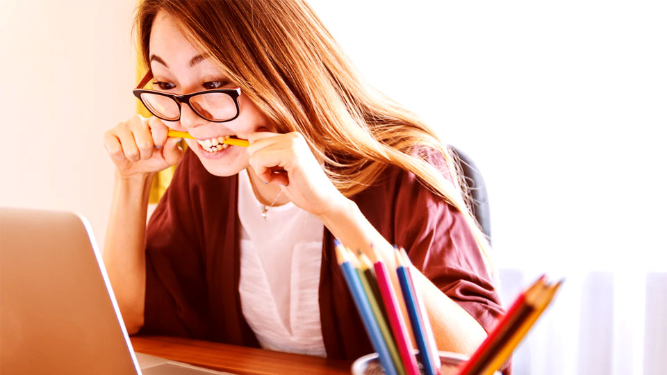 student looking at the notebook with a pencil in her mouth