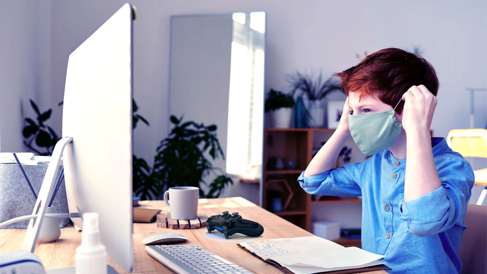 boy at computer desk with virus mask