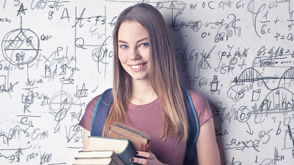 young woman standing on the school board and holding books