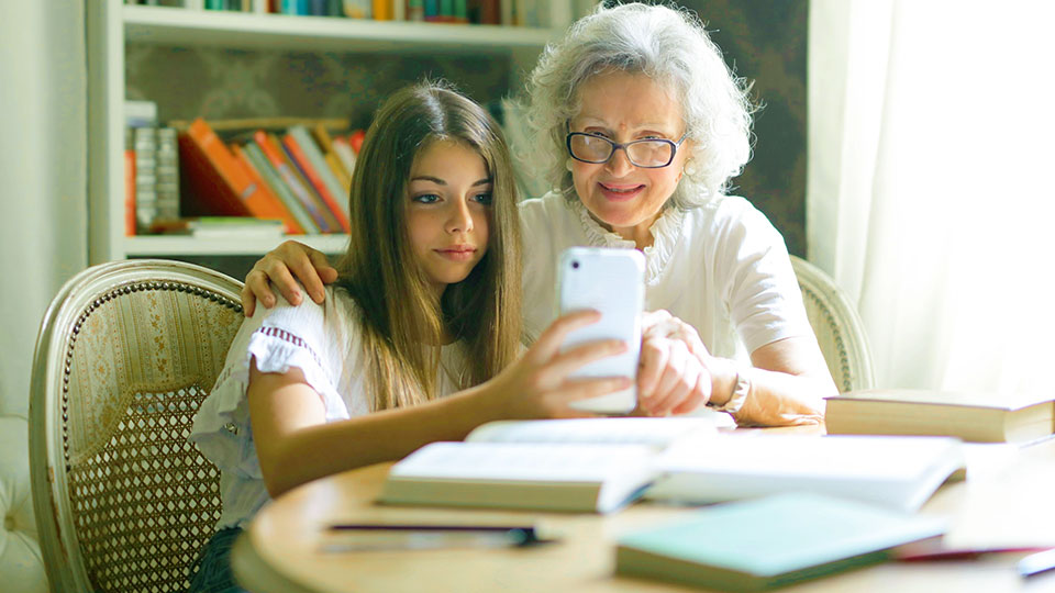 girl showing her smartphone to her grandmother