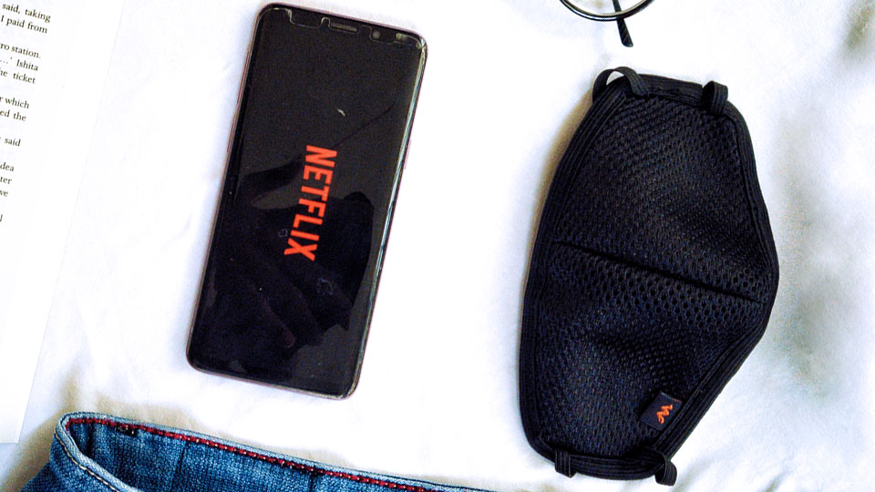 a smartphone with netflix next to a sanitary mask