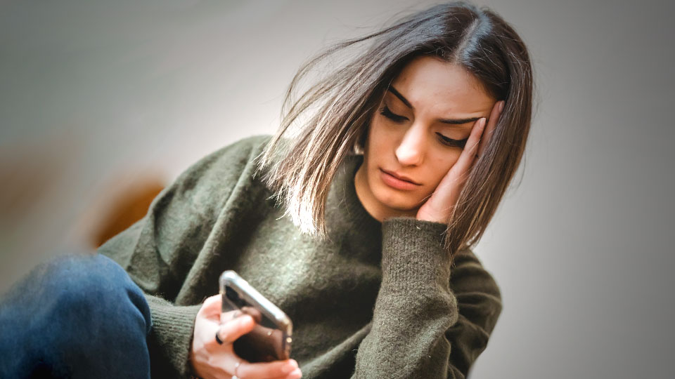 worried girl looking at her smartphone