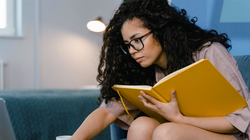 woman studying with a yellow notebook in her hand