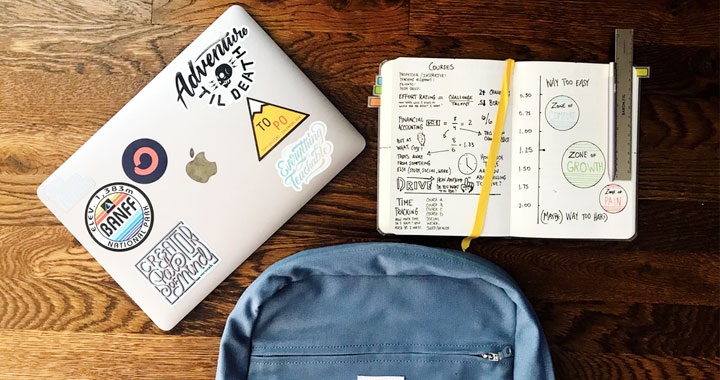 a laptop, a notebook and a backpack on the table