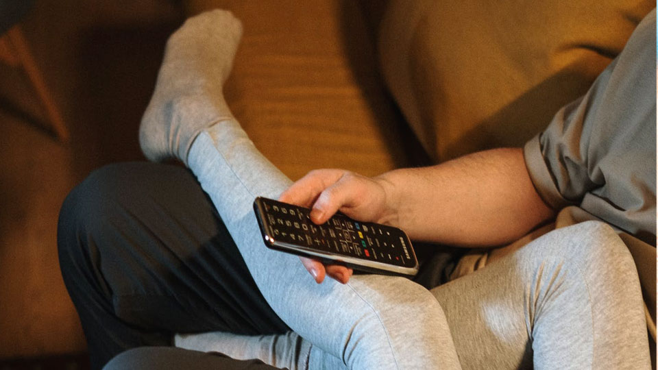 man holding remote control TV on sofa