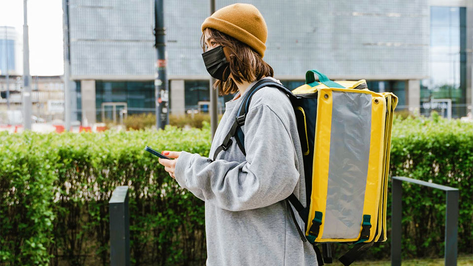 Woman wearing a sanitary mask with a phone in her hand making a delivery