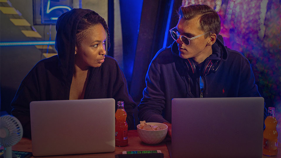 a woman and a man with laptops on the table