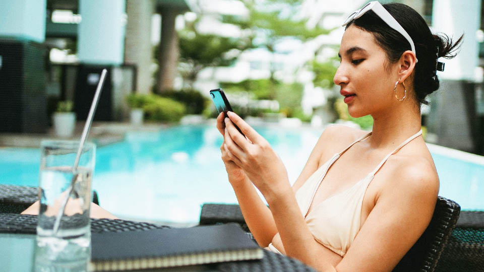woman with her phone in her hand beside the pool