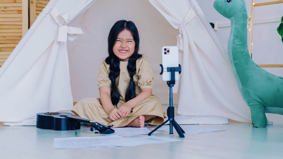 girl smiling at a smartphone on a tripod