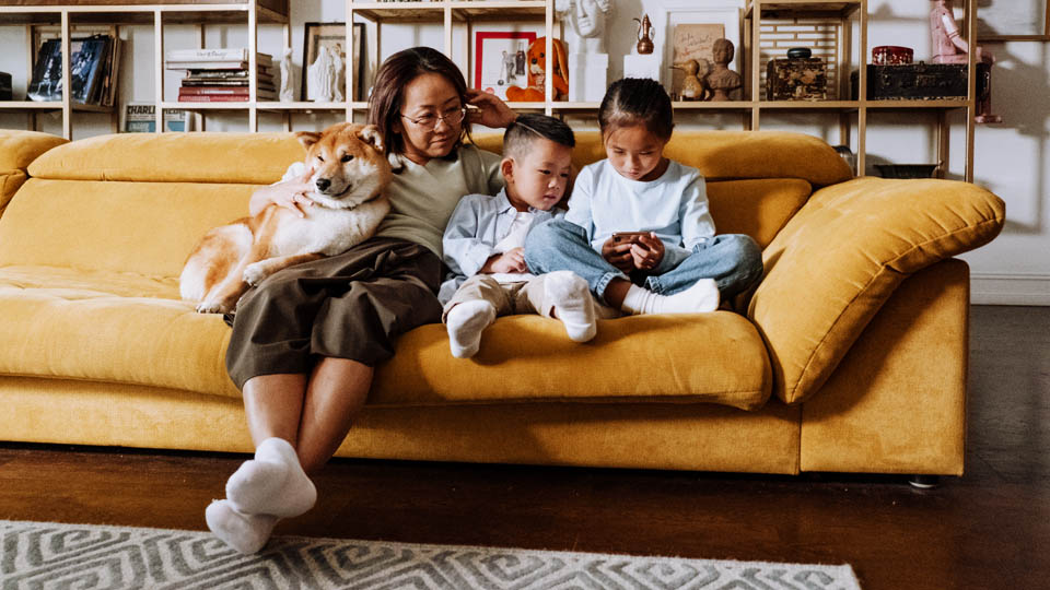 woman on the couch watching her children with a smartphone