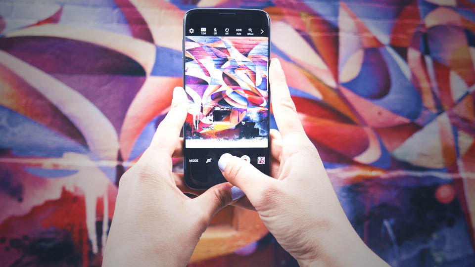 um smartphone nas mãos tirando foto de um muro colorido
