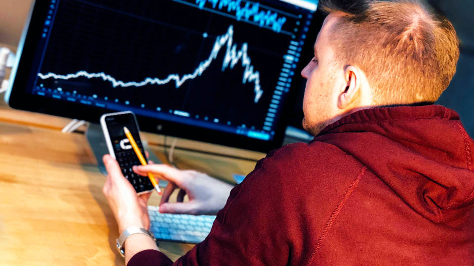 man at table with phone in hand consulting investments