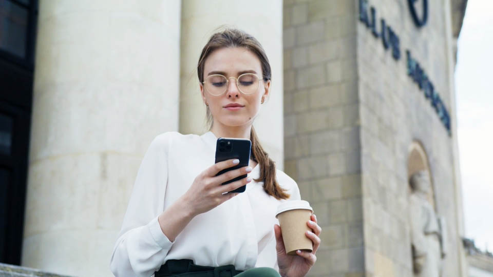 woman holding a smartphone and a coffee