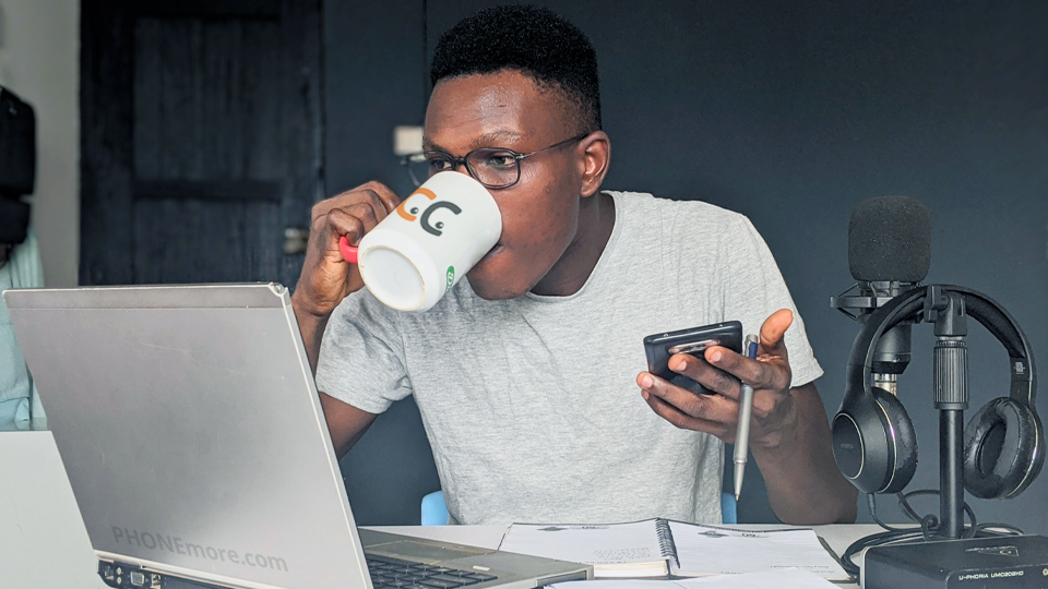 un homme travaillant avec un ordinateur portable, buvant du café et tenant un téléphone