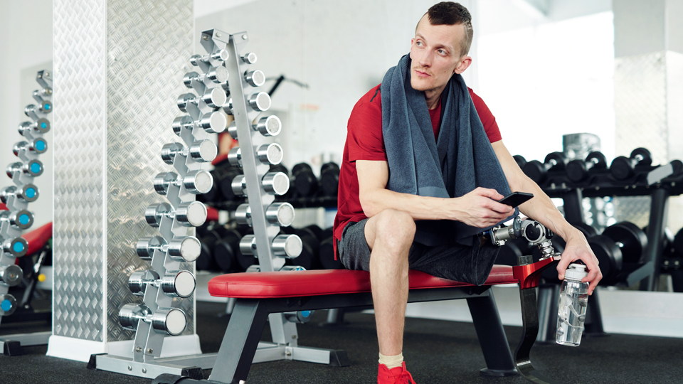 a man in the gym sitting holding a phone
