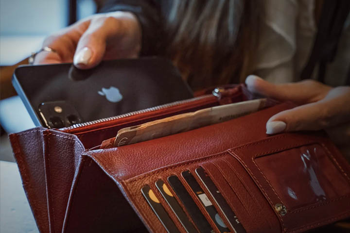 putting a smartphone in a leather wallet with credit cards and cash