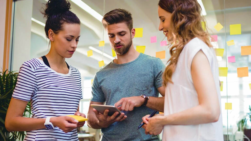 three people looking at a mobile project on a tablet