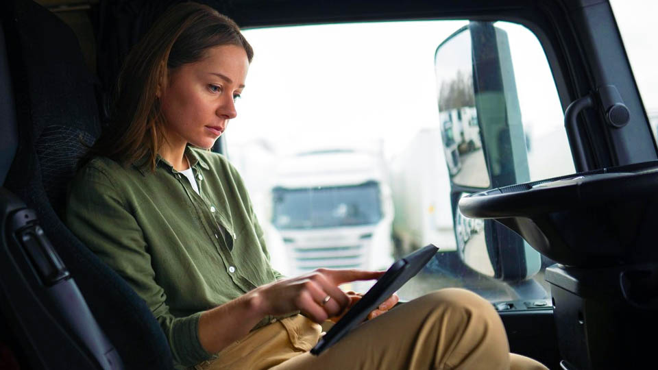 une femme assise à l'intérieur d'un camion regarde et manipule une tablette
