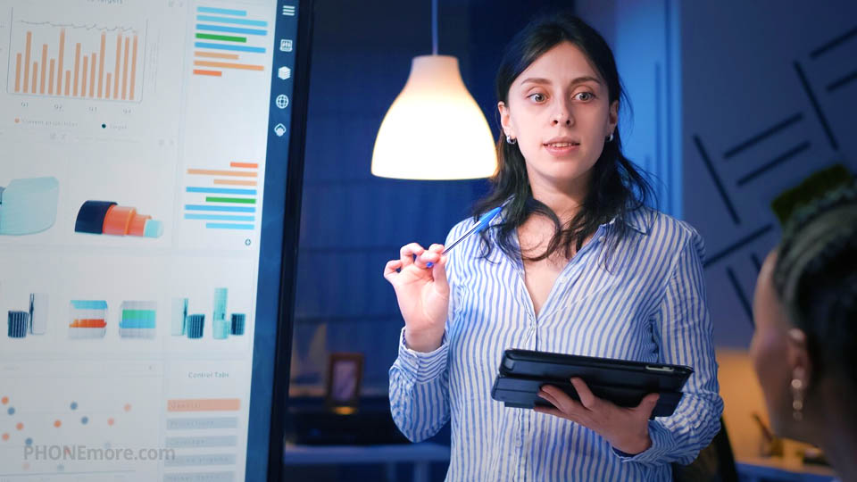 a woman holding a tablet in the office and presenting a dashboard