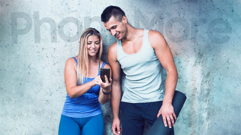 a fitness woman and man in the gym looking at a smartphone