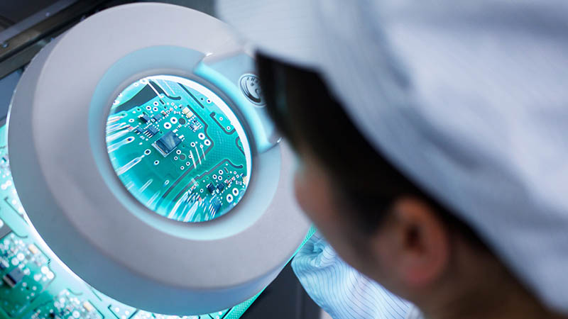 une personne regardant une puce électronique dans une usine