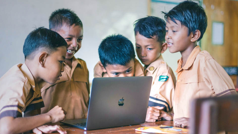 children smiling using a macbook