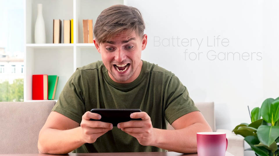 excited young man sits at table holding and looking at phone inside living room
