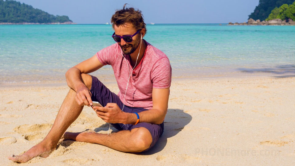 man on the beach with a smartphone in his hands