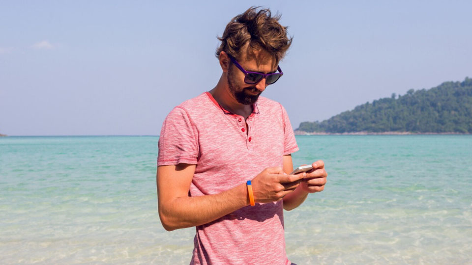 man on the beach with a smartphone in his hands