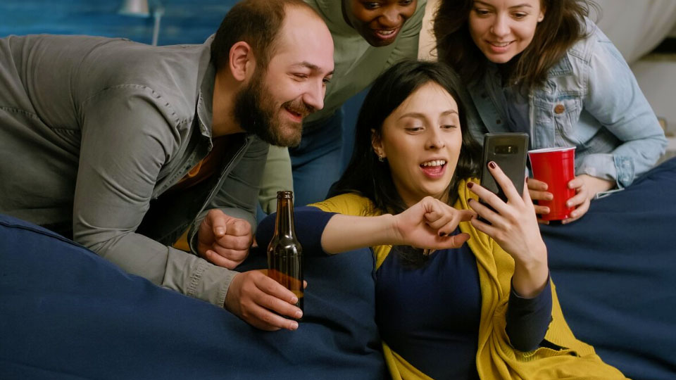 quattro persone che si divertono sul divano guardando il cellulare