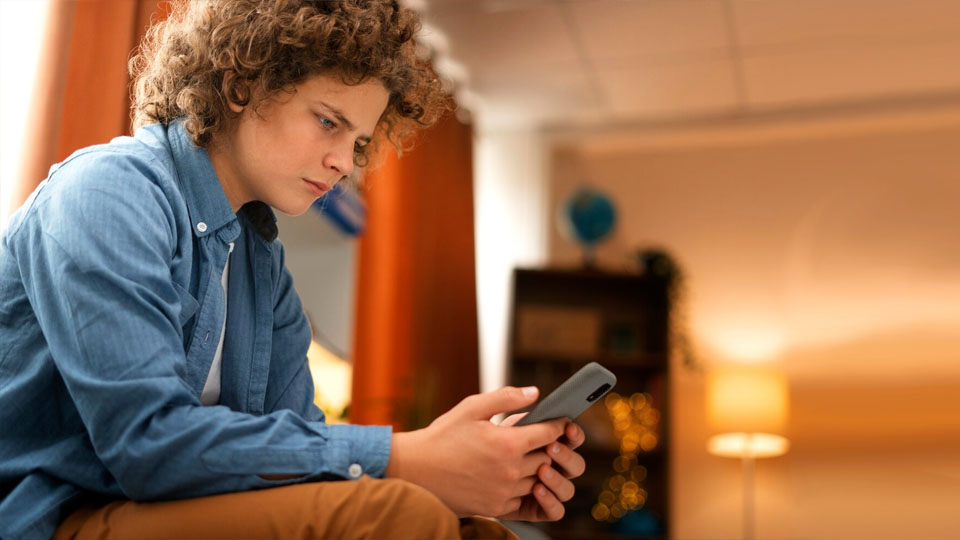 une personne inquiète regardant son téléphone portable et assise sur le canapé