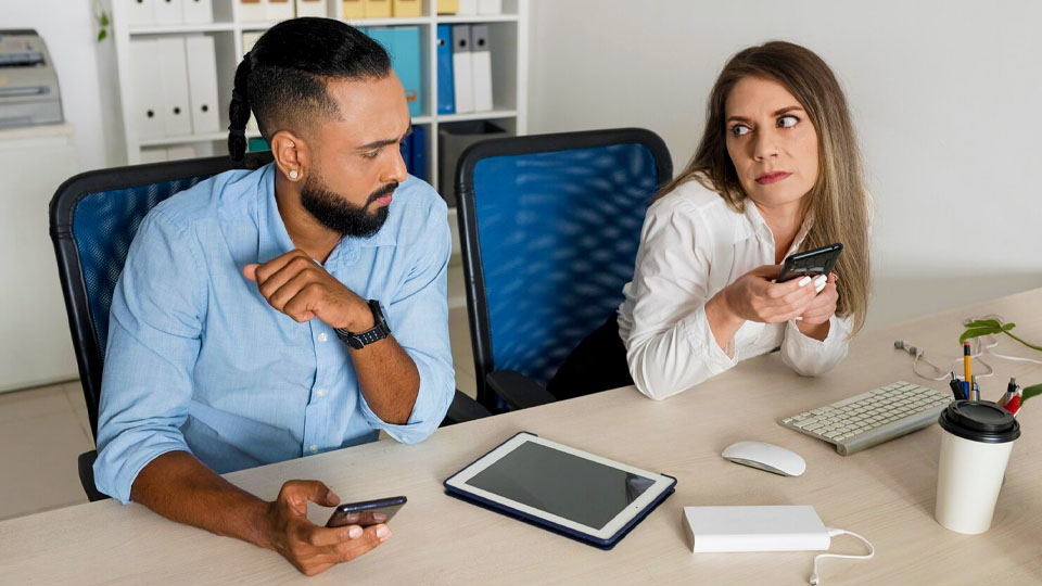 a woman and a man at work each with their smartphone in hand