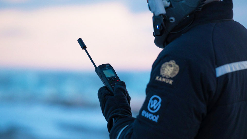 satellite phone in the hands of a man in overalls and a helmet