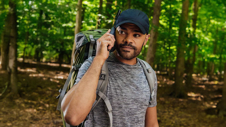 man in the forest with his satellite phone in his hands