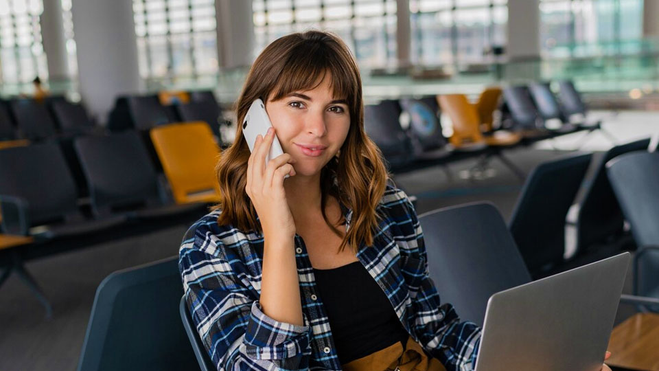 jeune passager avec smartphone et ordinateur portable assis dans le terminal de l'aéroport
