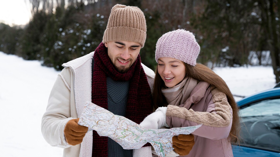 a traveling couple dressed in winter clothes looking at a paper map