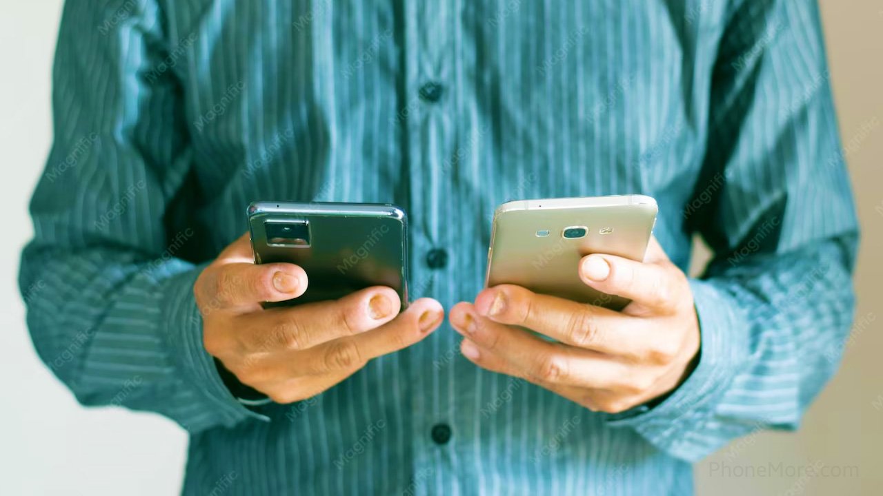 a man's hands holding two smartphones in each hand
